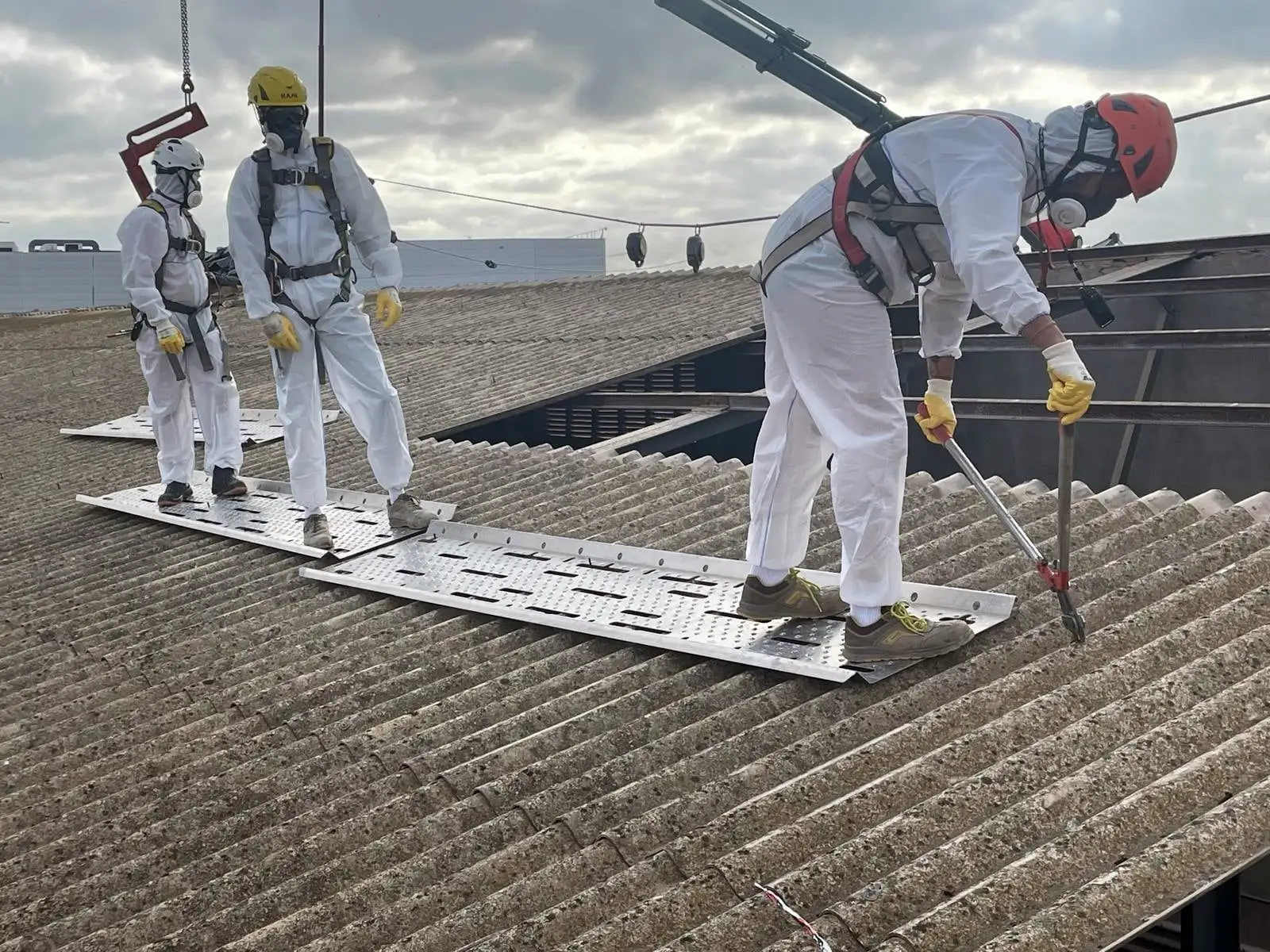 Chantier professionnel de retrait de plaques de toiture en fibrociment avec équipements de protection